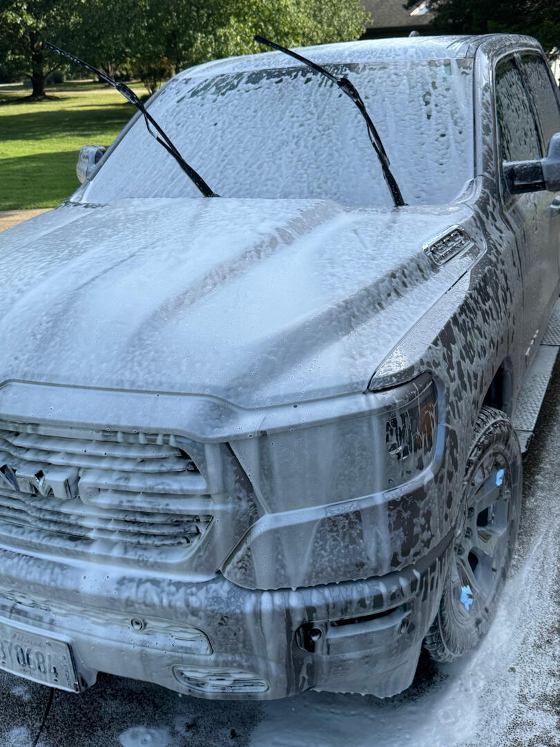 Silver Ram truck covered in foam during exterior detailing